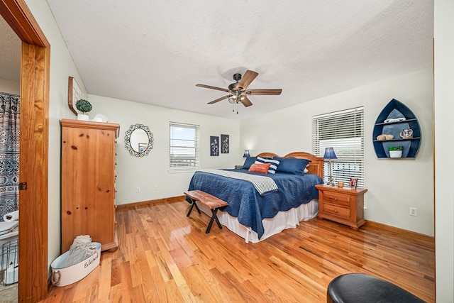 bedroom featuring light wood finished floors, baseboards, a textured ceiling, and ceiling fan