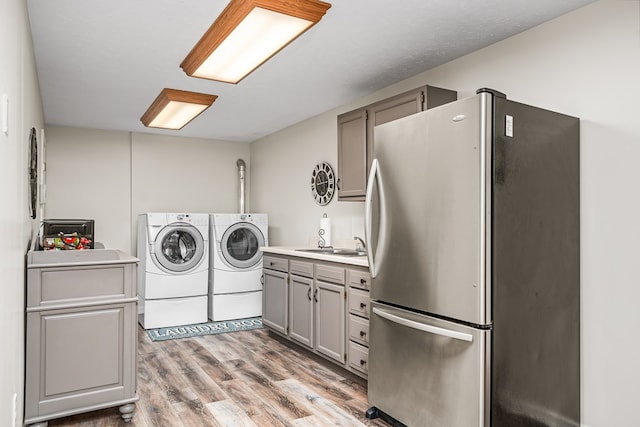 washroom featuring washer and dryer, a sink, laundry area, and light wood-type flooring