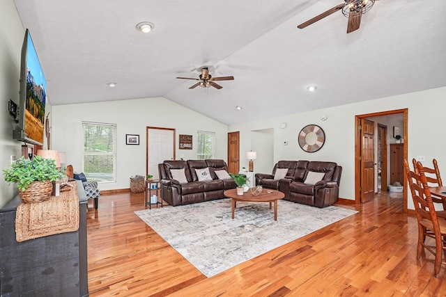 living area with light wood-style flooring, vaulted ceiling, and ceiling fan