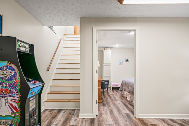 staircase featuring wood finished floors, a textured ceiling, and baseboards