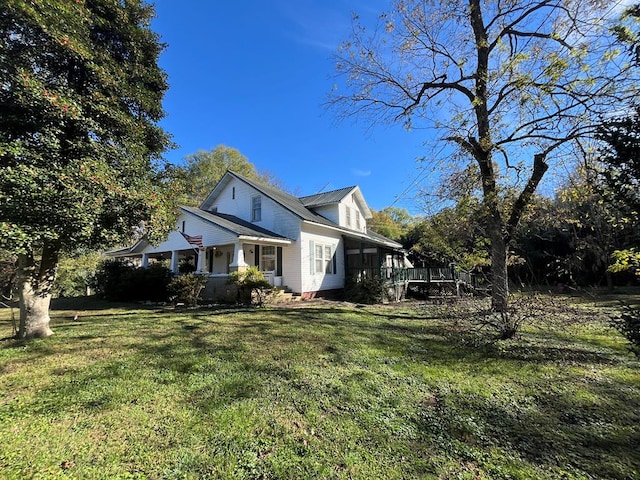 view of side of property featuring covered porch and a lawn