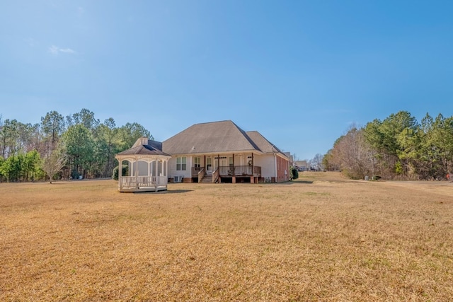 rear view of house with a gazebo, a wooden deck, and a lawn