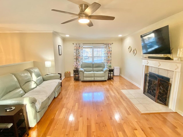 living room with a fireplace, light hardwood / wood-style flooring, ornamental molding, and ceiling fan