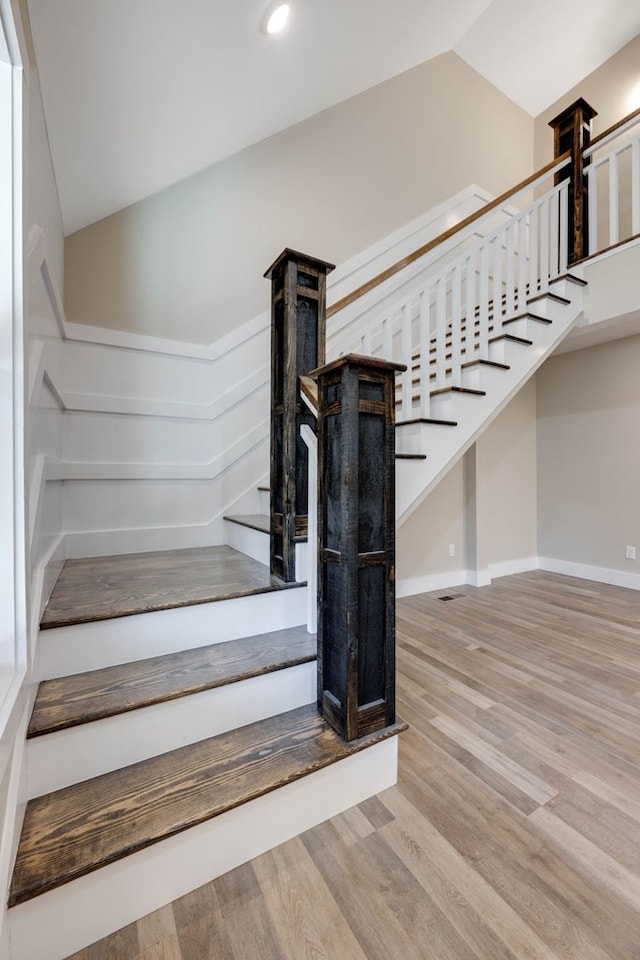 staircase featuring recessed lighting, vaulted ceiling, baseboards, and wood finished floors