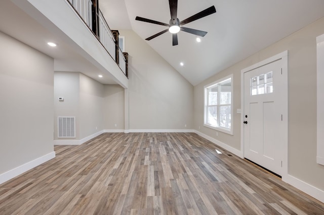 entrance foyer with visible vents, a ceiling fan, high vaulted ceiling, light wood-type flooring, and baseboards