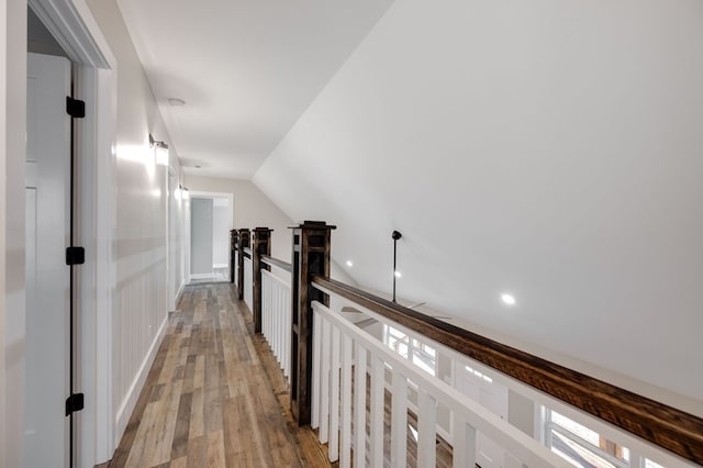 hallway with lofted ceiling and hardwood / wood-style floors