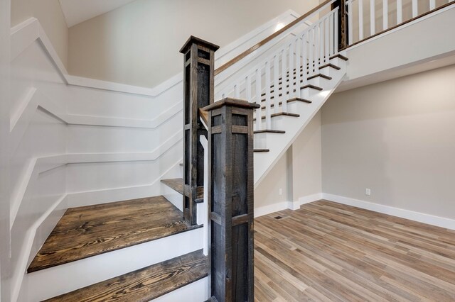 staircase featuring wood finished floors and baseboards