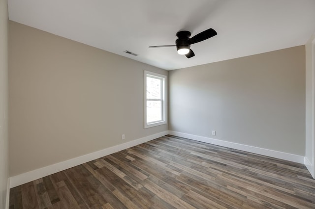 spare room featuring a ceiling fan, visible vents, baseboards, and wood finished floors