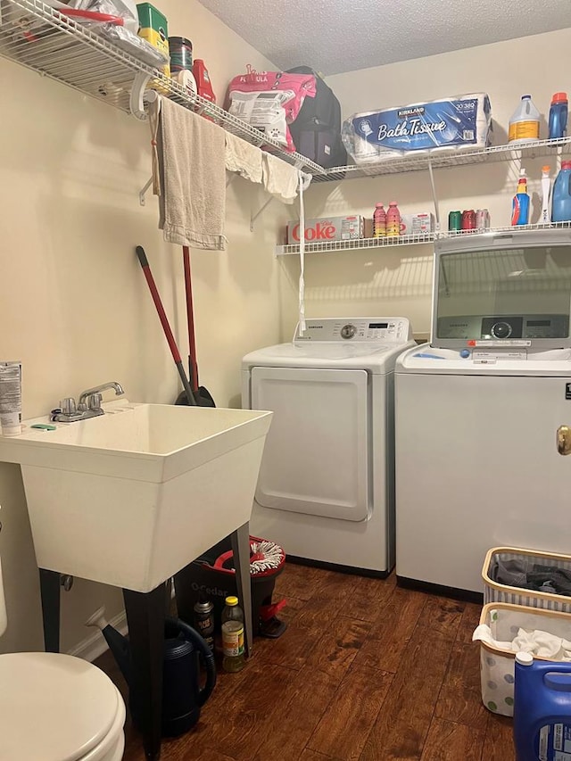 clothes washing area with dark hardwood / wood-style flooring, sink, washing machine and dryer, and a textured ceiling