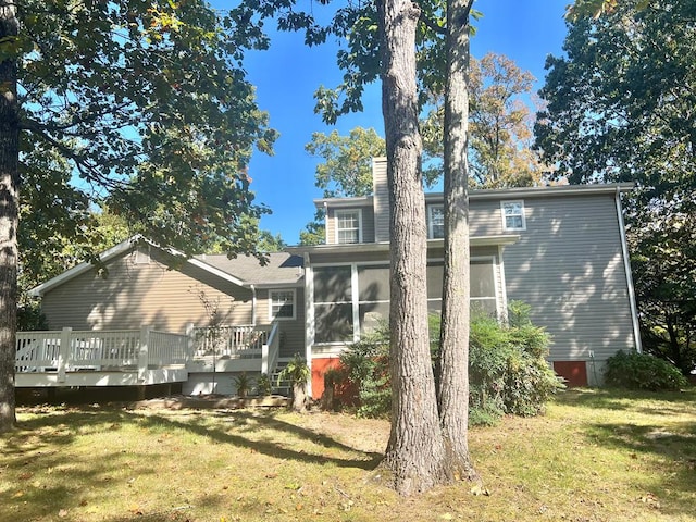 rear view of house with a wooden deck, a sunroom, and a yard