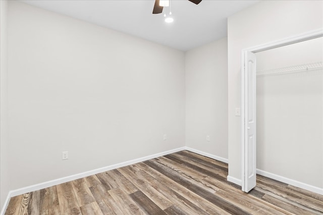 unfurnished bedroom featuring wood finished floors, baseboards, a closet, and ceiling fan