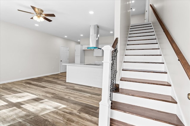 stairs with wood finished floors, recessed lighting, a ceiling fan, and baseboards