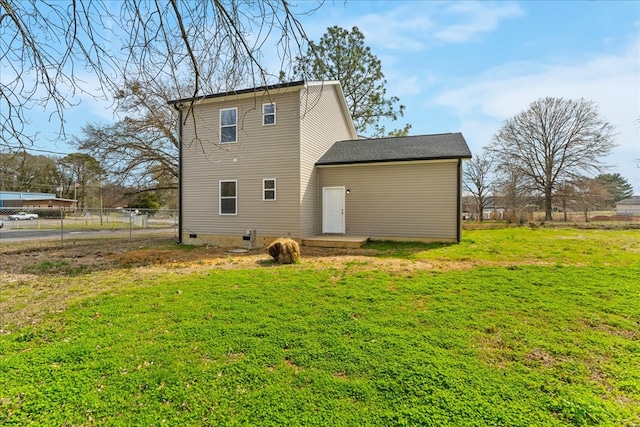 rear view of house featuring a yard and fence