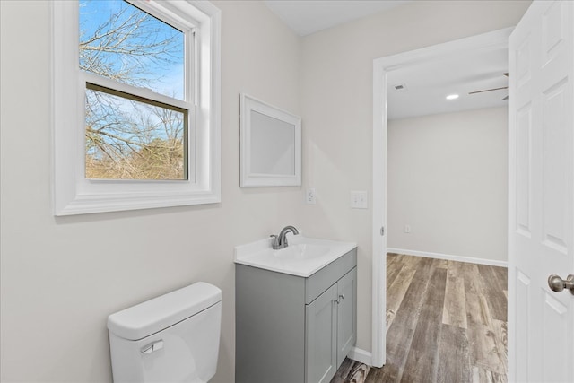 bathroom featuring vanity, toilet, wood finished floors, and baseboards