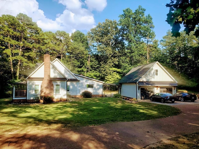 exterior space featuring a detached garage, a chimney, and a front lawn