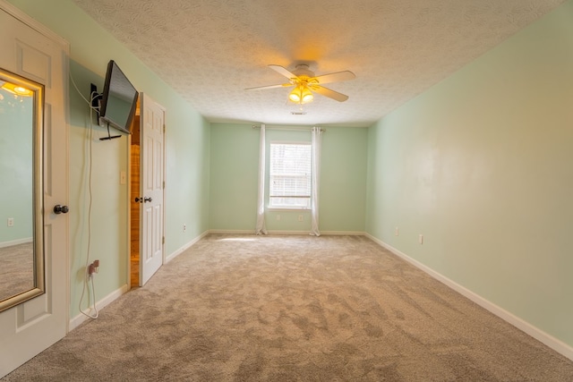 spare room featuring ceiling fan, light colored carpet, and a textured ceiling