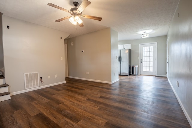 unfurnished living room with dark hardwood / wood-style flooring, ceiling fan, and a textured ceiling