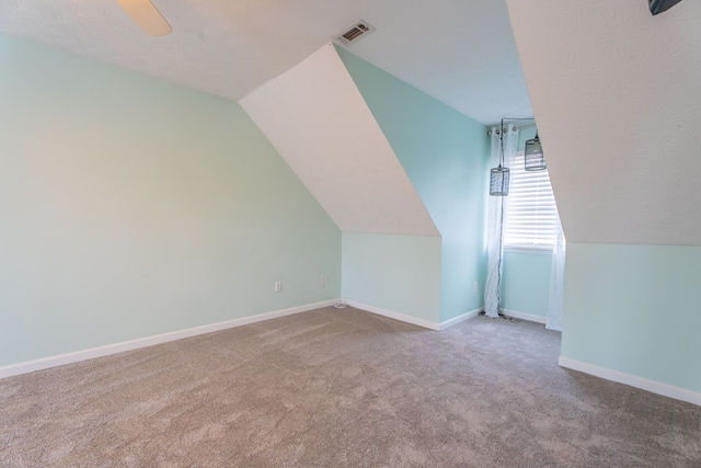 additional living space with light carpet, ceiling fan, vaulted ceiling, and a textured ceiling