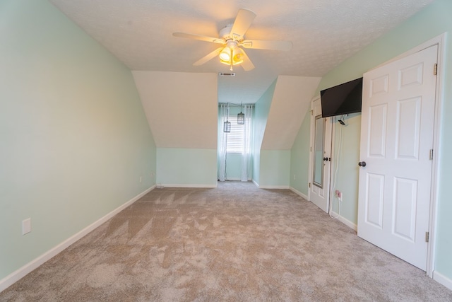 additional living space featuring ceiling fan, lofted ceiling, light carpet, and a textured ceiling