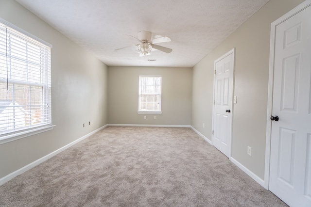 spare room featuring ceiling fan, light colored carpet, and a textured ceiling