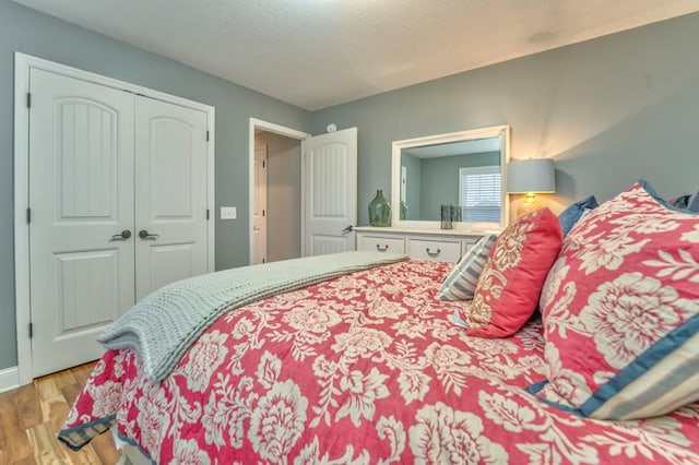 bedroom with a closet, light wood-style floors, and a textured ceiling