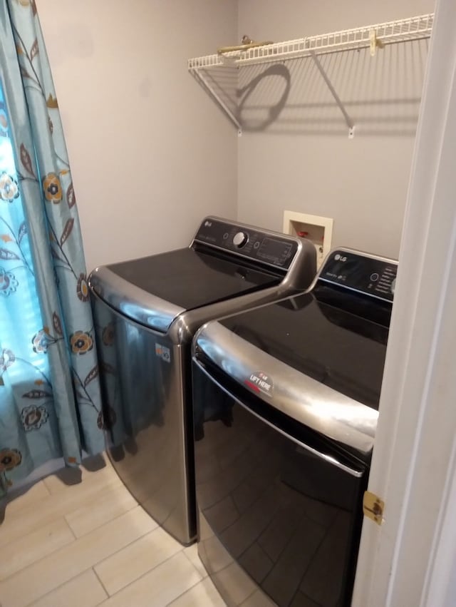 clothes washing area featuring washing machine and dryer and light wood-type flooring