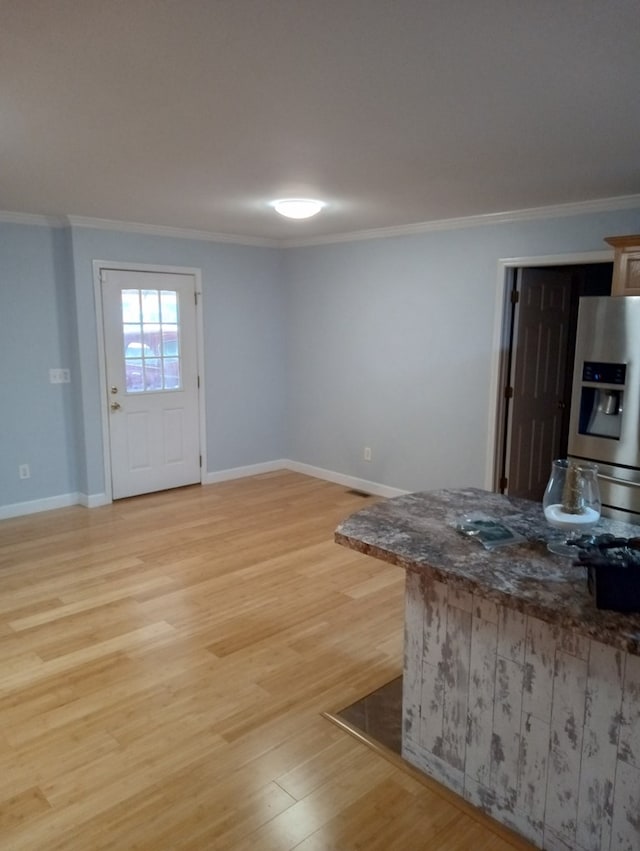 kitchen with crown molding, dark stone counters, stainless steel fridge with ice dispenser, and light wood-type flooring