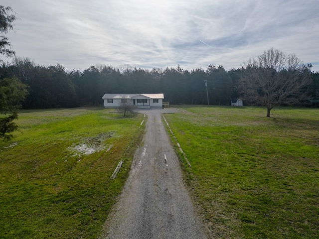 view of street with a rural view, driveway, and a wooded view