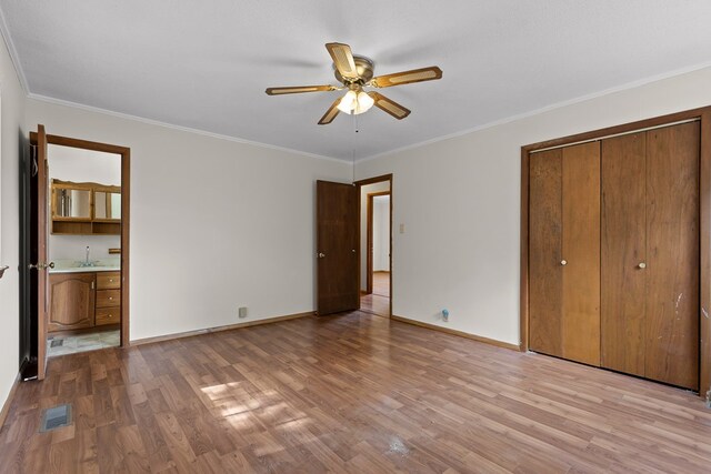 unfurnished bedroom with baseboards, wood finished floors, a sink, and ornamental molding