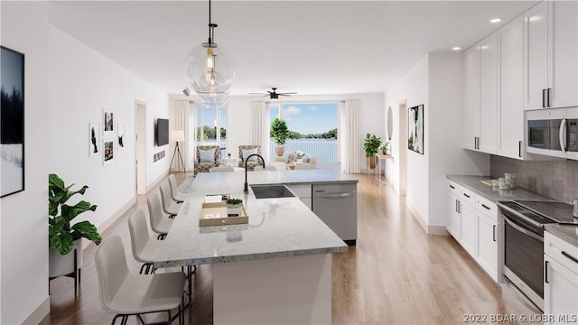 kitchen with white cabinetry, sink, stainless steel appliances, decorative light fixtures, and decorative backsplash