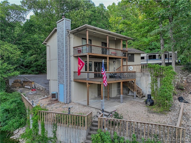 back of property with central AC, a wooden deck, a balcony, and a patio