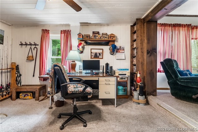 carpeted office featuring ceiling fan and wooden walls