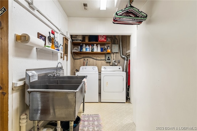 laundry room featuring washing machine and dryer, sink, and a textured ceiling