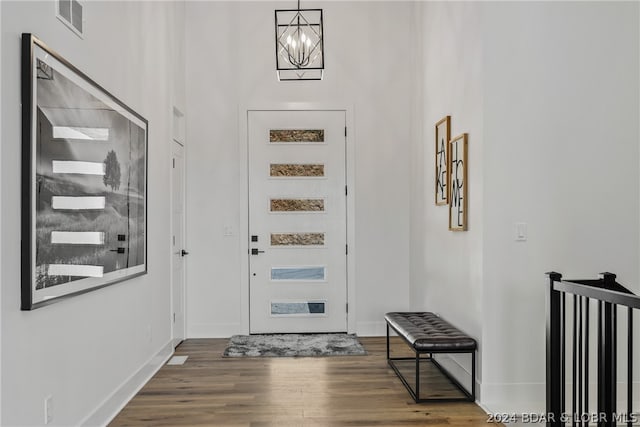 entryway with a high ceiling, hardwood / wood-style floors, and a chandelier