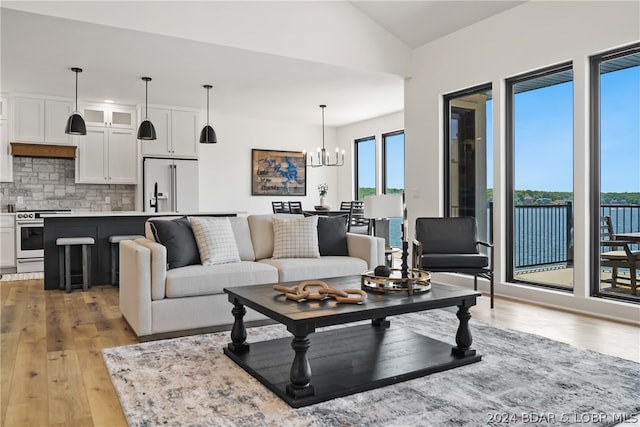 living room featuring a notable chandelier, lofted ceiling, and light wood-type flooring