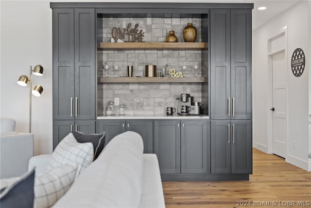 bar featuring decorative backsplash, gray cabinets, and light wood-type flooring