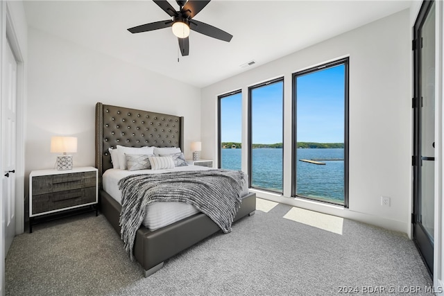 carpeted bedroom with a water view and ceiling fan