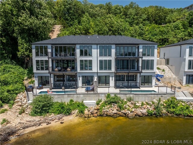 back of house with a patio, a water view, and a balcony