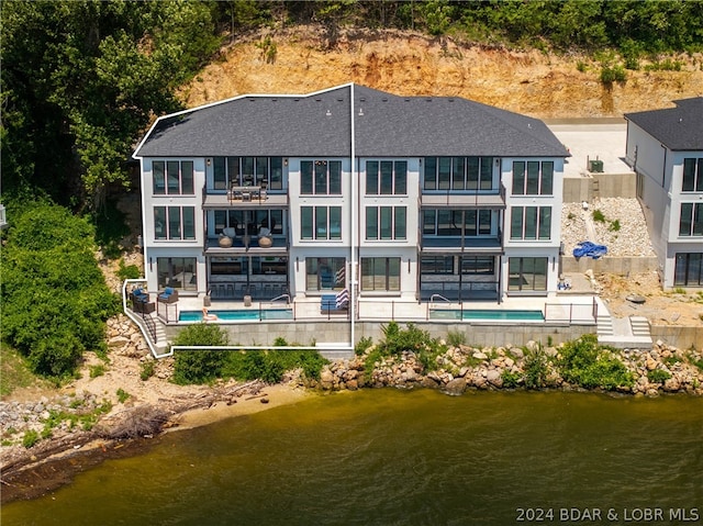 back of house featuring a water view and a patio area