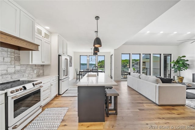 128 Palisades Yacht Club Dr, Lake Ozark, MO 65049 - kitchen with white cabinetry, white appliances, a kitchen breakfast bar, hanging light fixtures, and a center island with sink