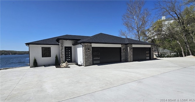 prairie-style house with a garage and a water view