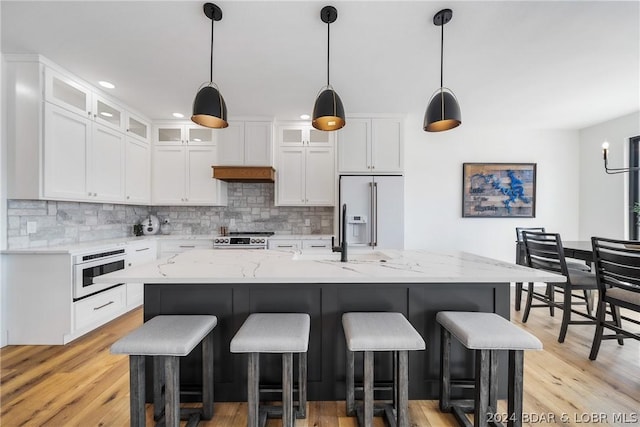 kitchen with white cabinets, a center island, high quality fridge, and stainless steel range