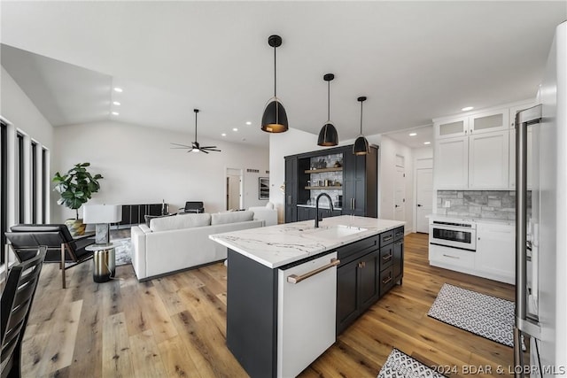 kitchen featuring white cabinets, white appliances, backsplash, hanging light fixtures, and a kitchen island with sink