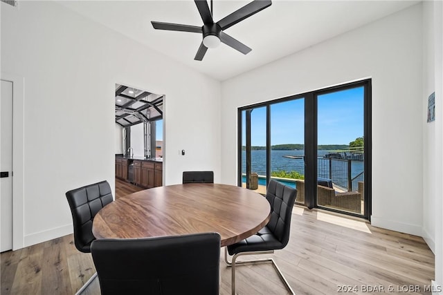 dining room with ceiling fan, light hardwood / wood-style floors, and a water view