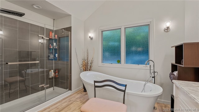 bathroom with vanity, plus walk in shower, hardwood / wood-style floors, and vaulted ceiling