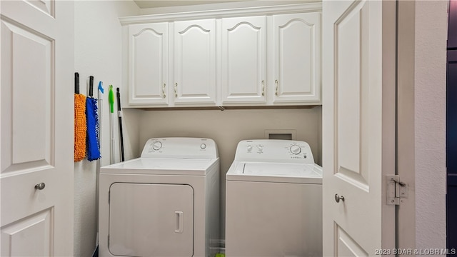 washroom with washer and dryer and cabinets