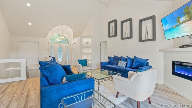 living room with a notable chandelier, vaulted ceiling, and light hardwood / wood-style floors