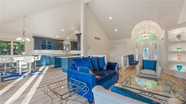 living room with light hardwood / wood-style floors, a chandelier, and high vaulted ceiling