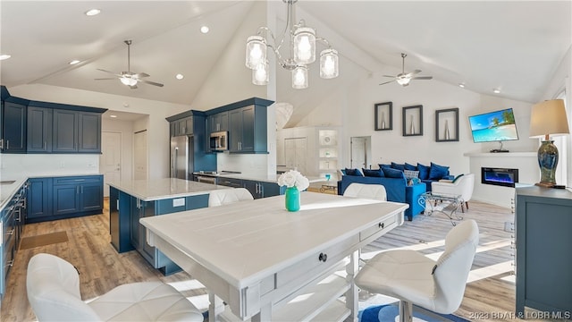 kitchen with appliances with stainless steel finishes, ceiling fan with notable chandelier, and light hardwood / wood-style floors