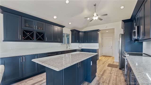 kitchen featuring ceiling fan, sink, a kitchen island, light stone countertops, and light hardwood / wood-style floors